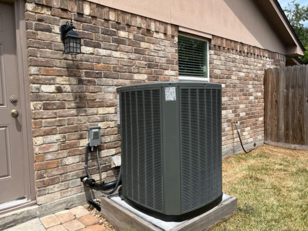 A condenser installed on a pad beside a brick home